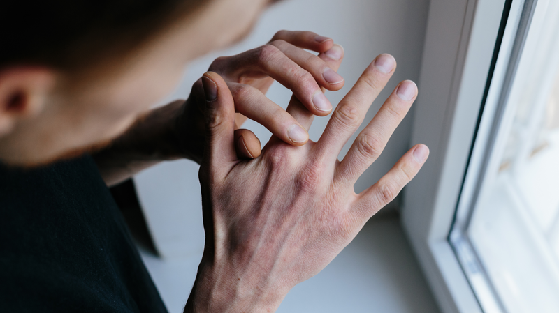 man looking at knuckles on his hand