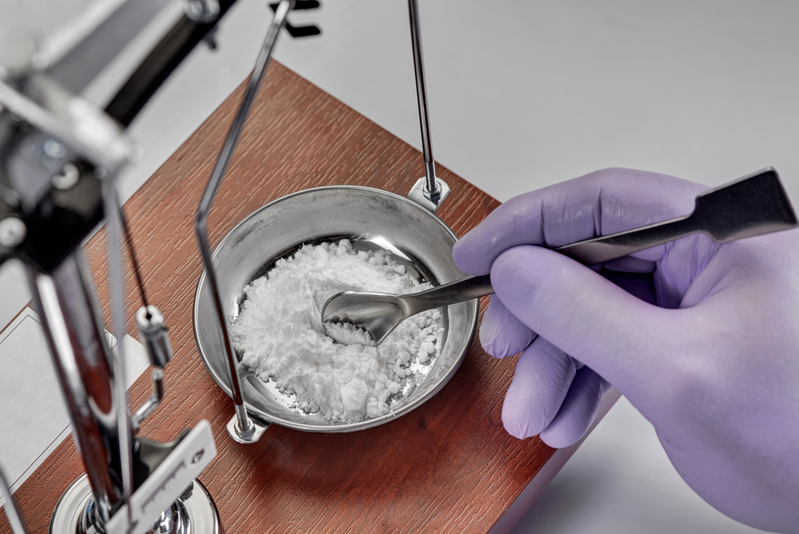 gloved hand mixing ingredients in compound pharmacy