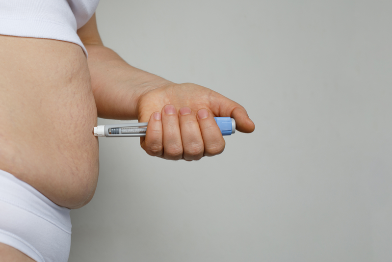 hand injecting weight loss drug into stomach