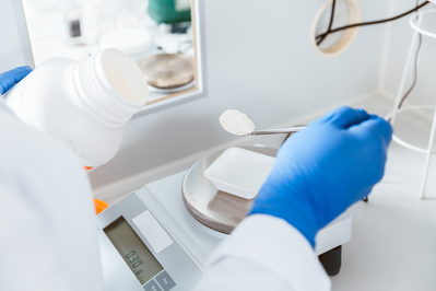 Closeup,Of,Pharmacist,Hand,Holding,Bottle,While,Weighing,White,Powder